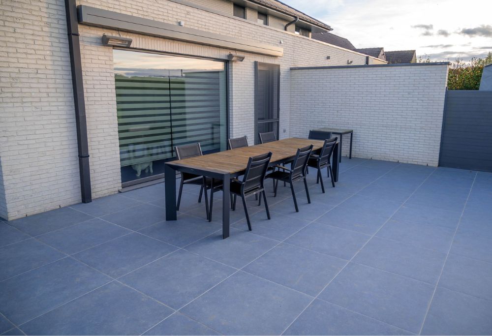 Een patio met een tafel en stoelen voor een huis. Tuinpaden, terrassen & opritten
